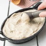 Scooping banana ice cream from an oval dish
