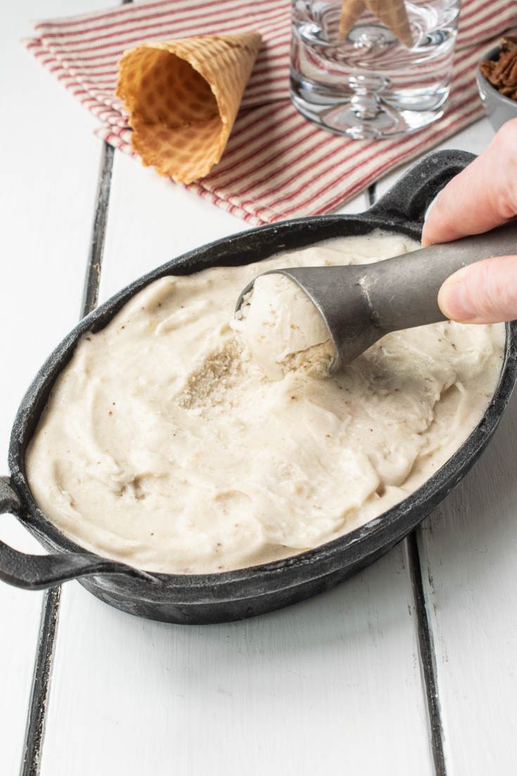 Scooping banana ice cream from an oval dish