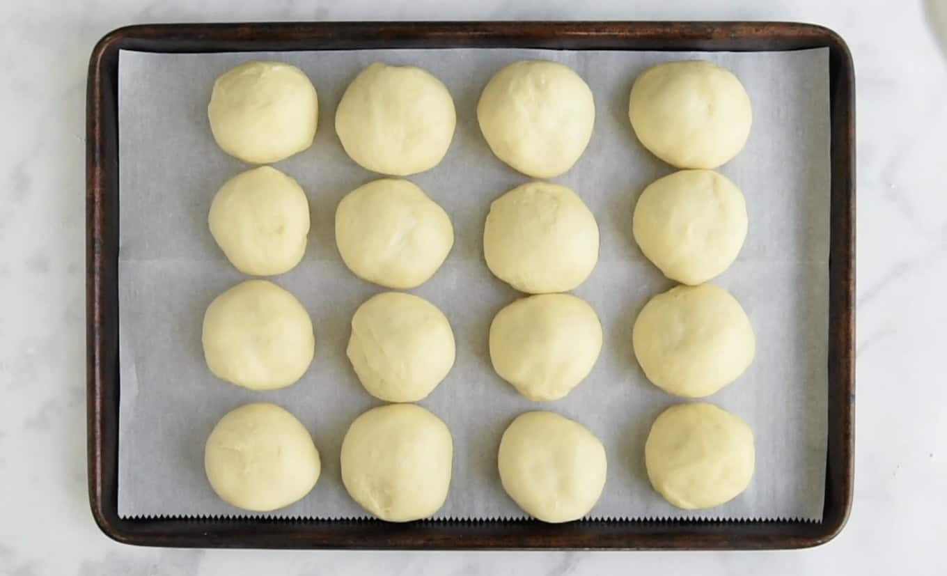 16 bread rolls on a baking sheet