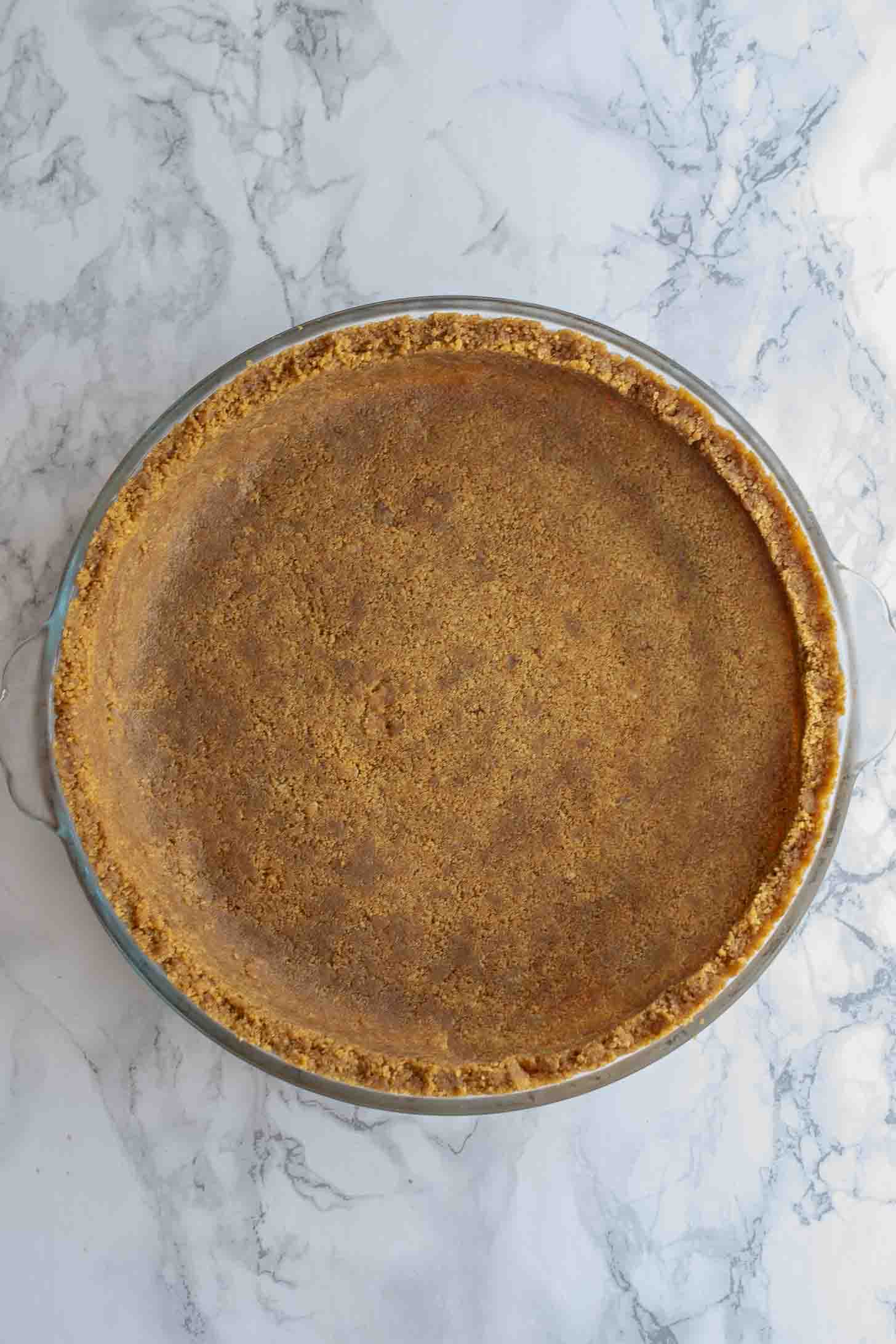 A gingersnap pie crust in a glass pan viewed from overhead