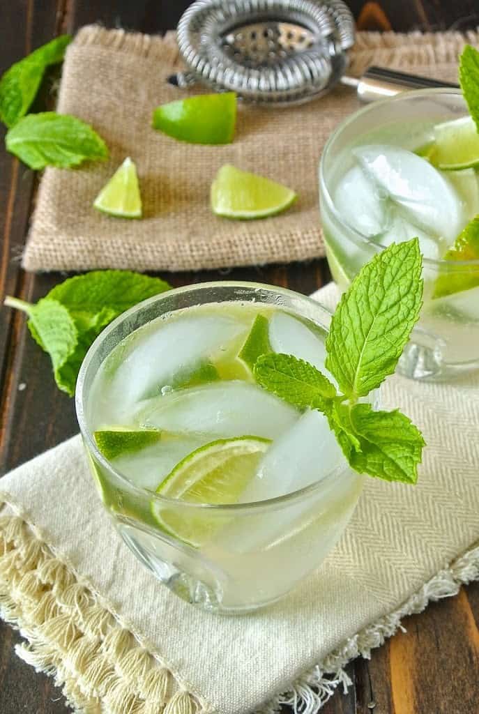 2 short glasses of ginger gin fizz with lime wedges and mint leaves