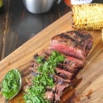 Perfectly grilled filet mignon sliced on a board with mint and parsley