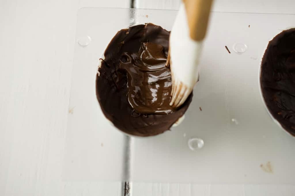 Brushing dark chocolate on the inside of an egg mould to make a chocolate egg shell