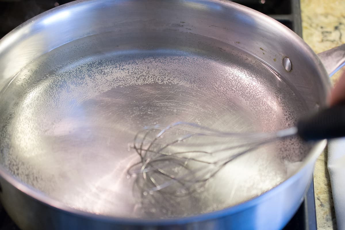 A pan of simmering water being whisked