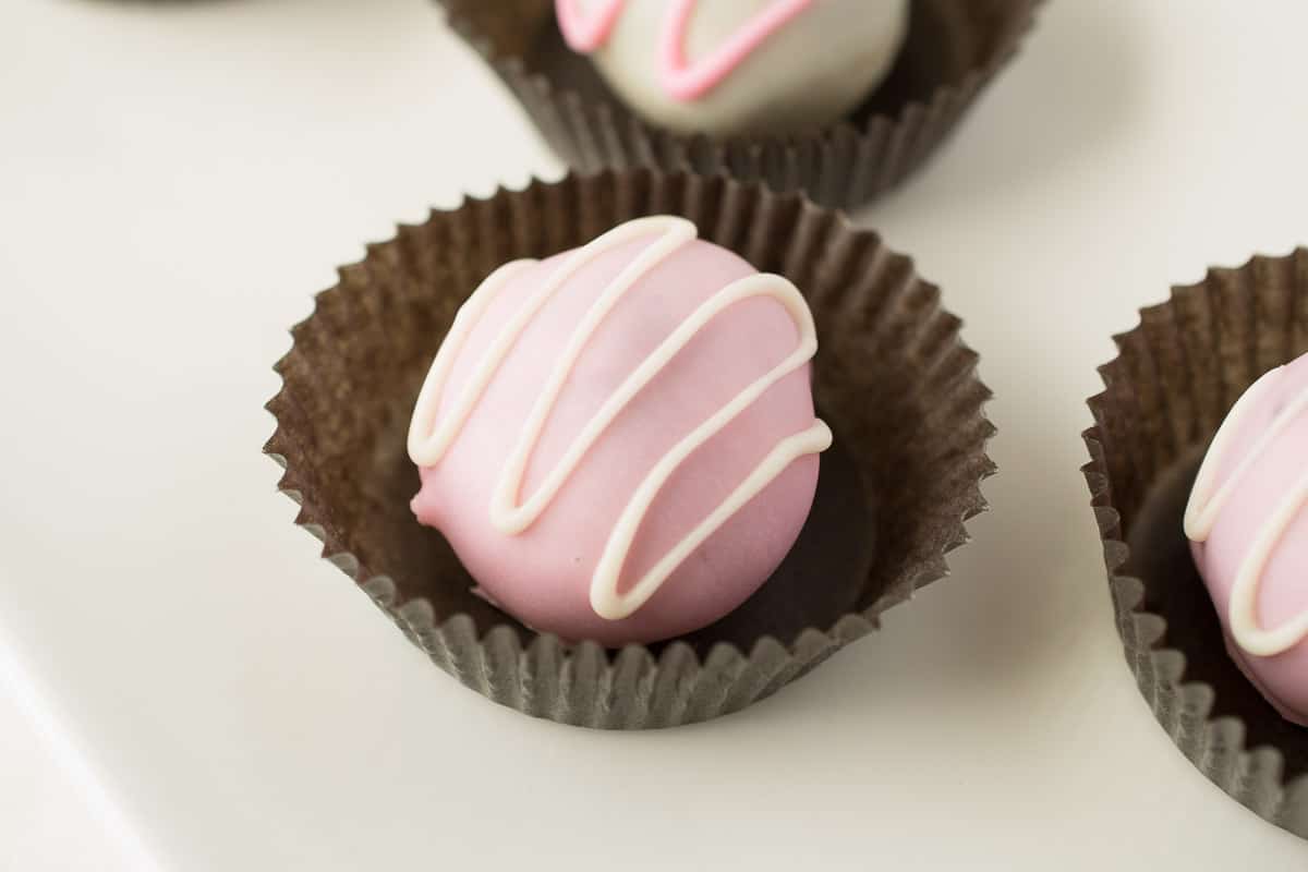 A pink, white chocolate truffle drizzled with white chocolate