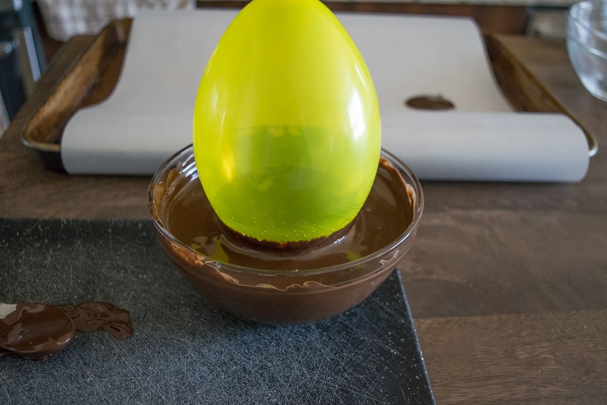 A balloon is dipped into melted chocolate to make a chocolate bowl