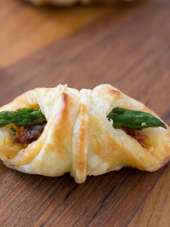 An asparagus sun-dried tomato puff pastry bite on a board