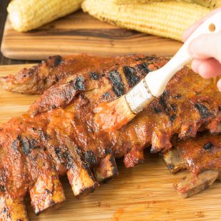 Brushing barbecue sauce on spare ribs