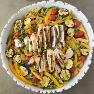 Pasta, grilled chicken and vegetables in a white bowl