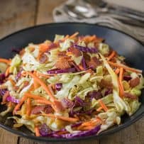 A closeup showing the red cabbage, green cabbage, orange carrot and crispy bacon