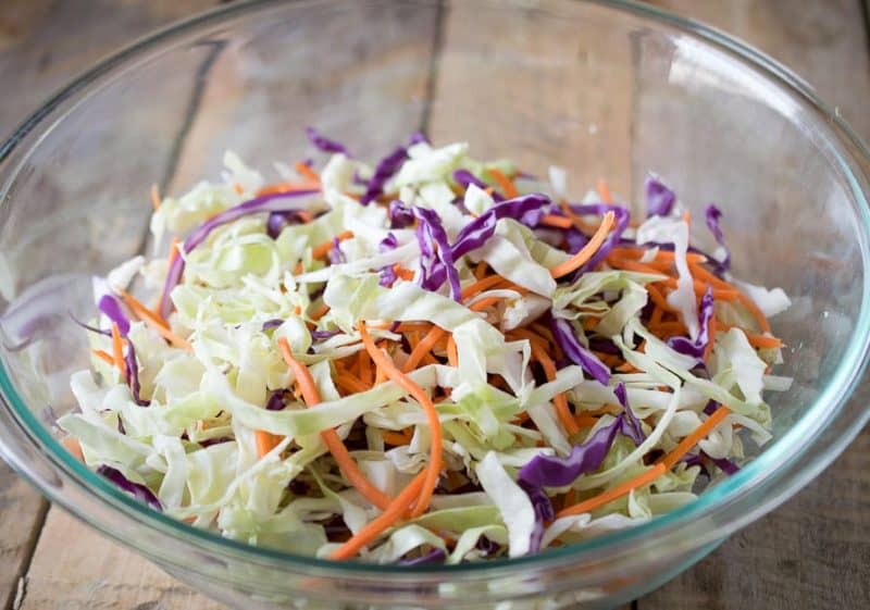 Shredded red and white cabbage and carrot in a glass bowl