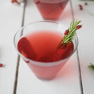 A Christmas Cosmopolitan with a stick of fresh rosemary