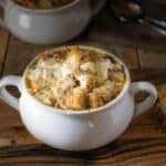 French onion soup in a white bowl with a side of cheese toast