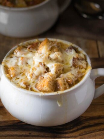 French onion soup in a white bowl with a side of cheese toast