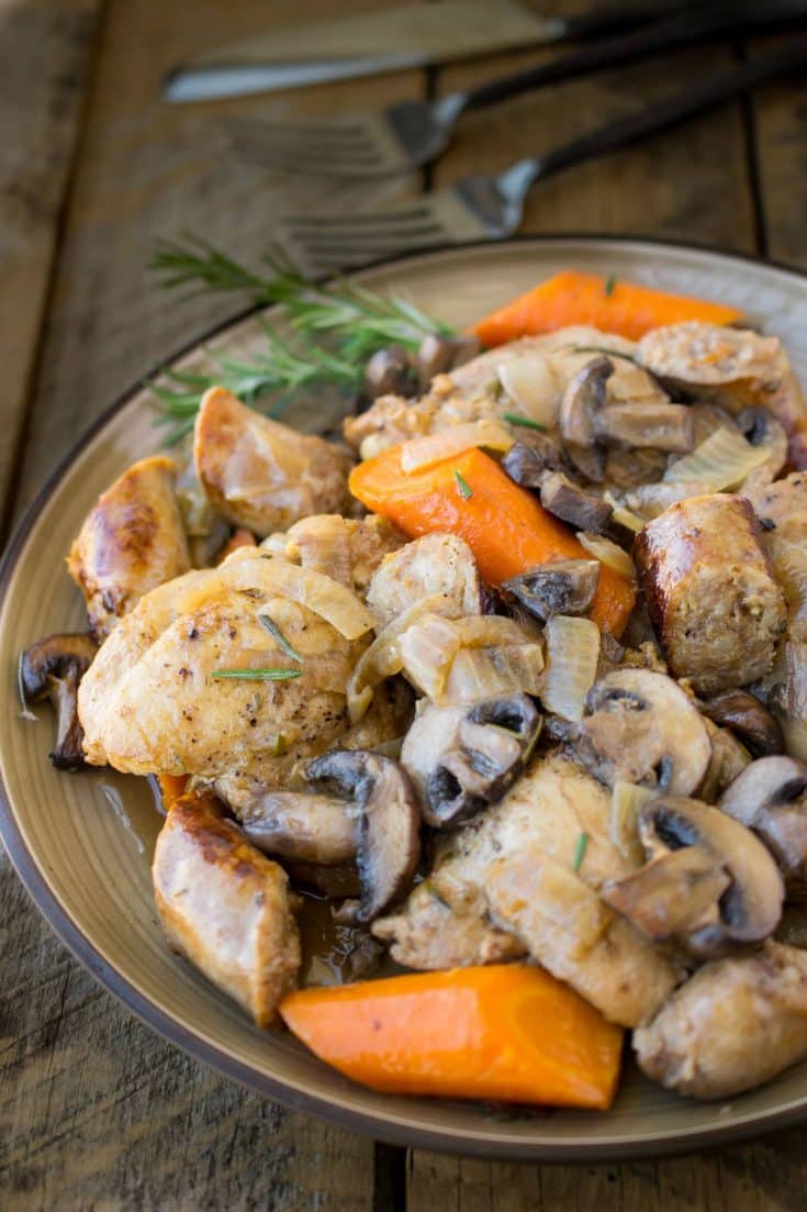 A plate of chicken and vegetables with fresh rosemary