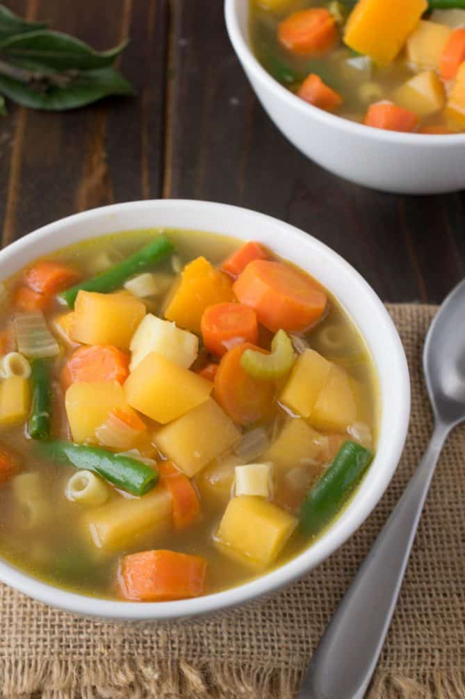 A closeup of vegetables in soup showing the carrots, green beans, butternut squash and rutabaga