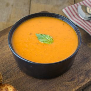 A bowl of 30 minute tomato basil soup on a board