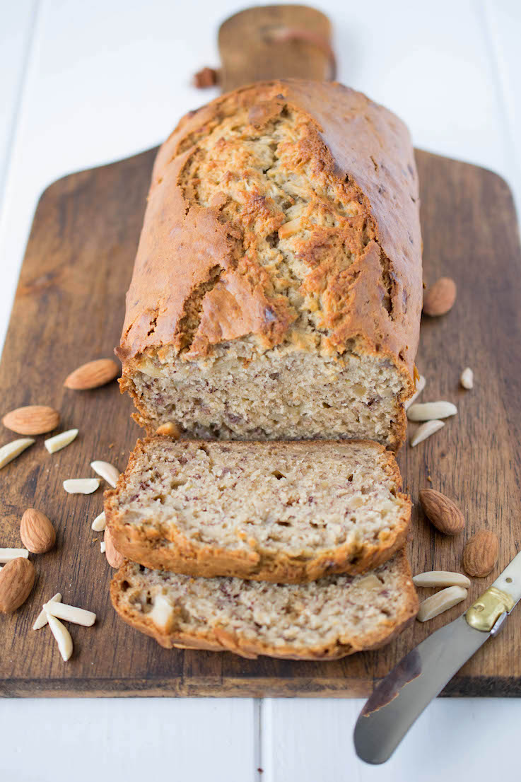 A loaf of almond banana bread on a serving board