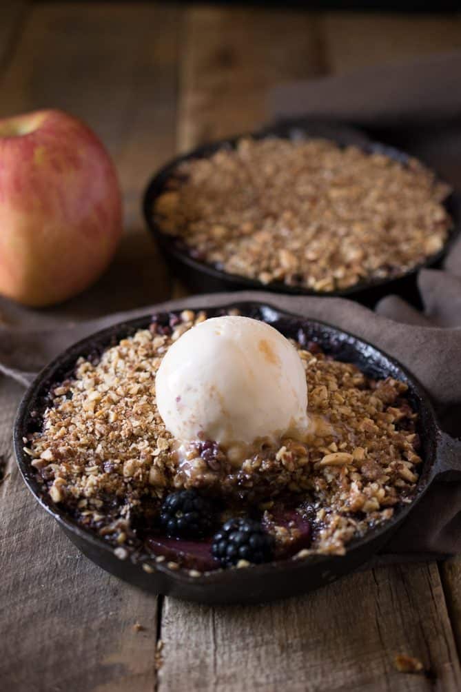 A scoop of ice cream slowly melting on top of an apple crumble
