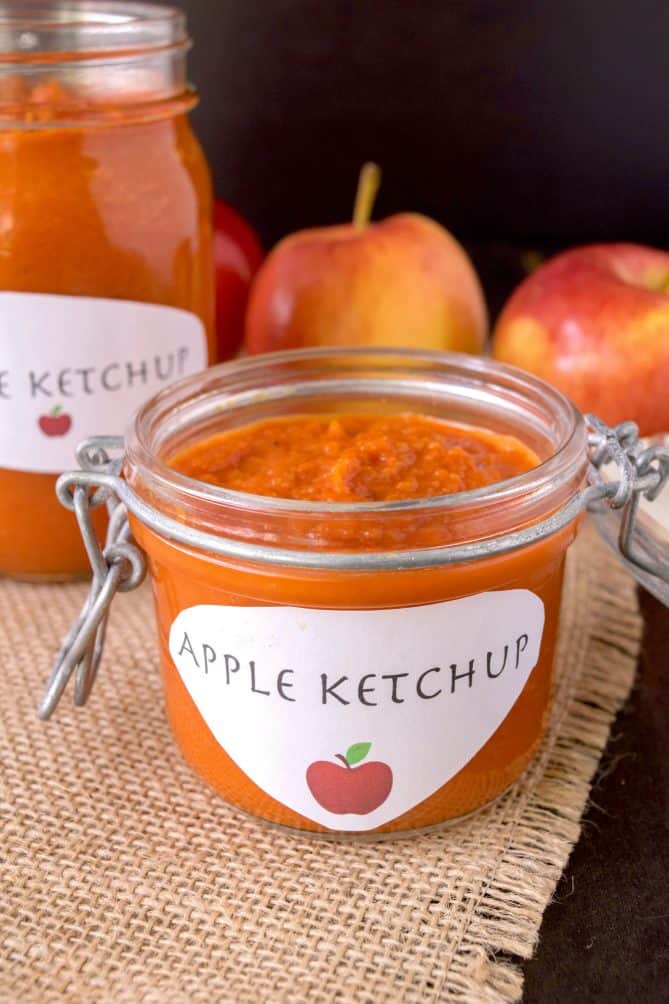 A pop-top jar filled with curry ketchup with a homemade label with an apple