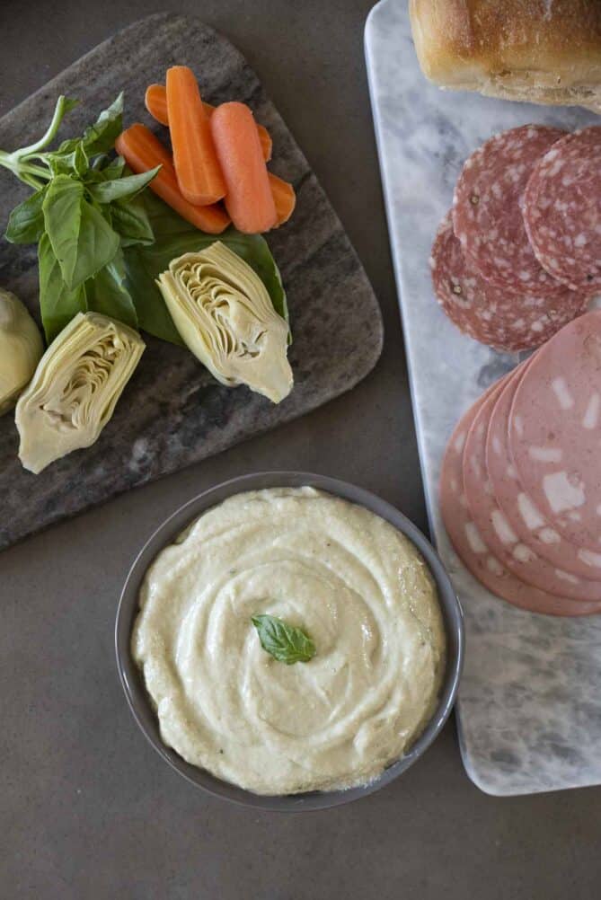 Blended artichokes with ricotta in a bowl with slices meats and vegetables