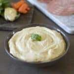 Artichoke cream in a bowl with fresh artichokes behind