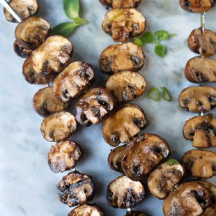 Mushrooms cut in half and threaded onto skewers and grilled