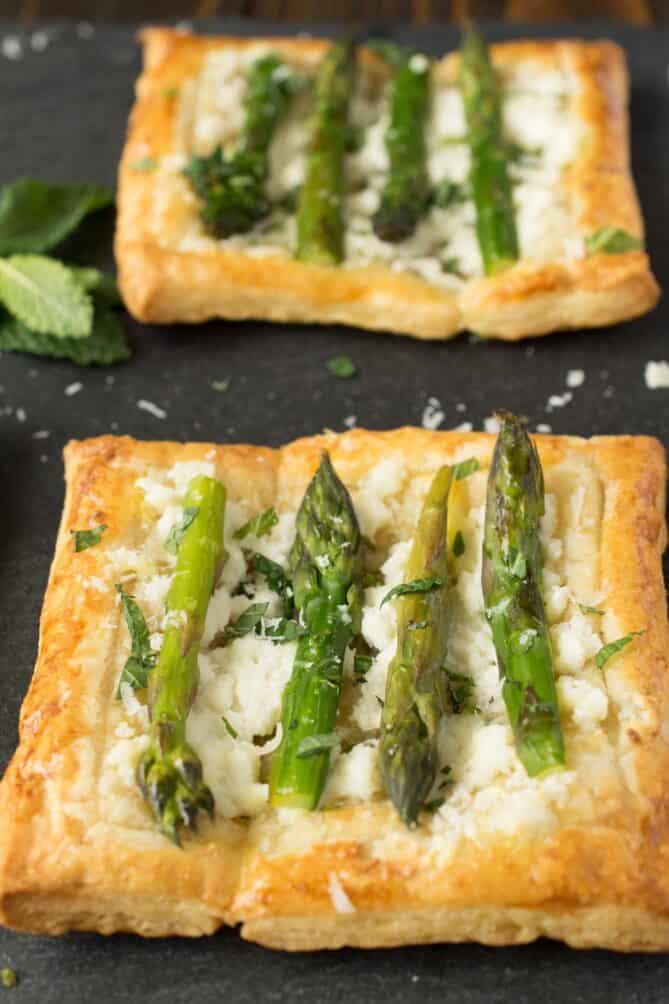 4 asparagus spears on top of ricotta and golden brown puff pastry