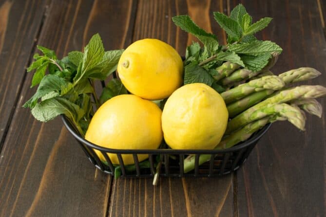 A basket of fresh asparagus, lemons and fresh mint