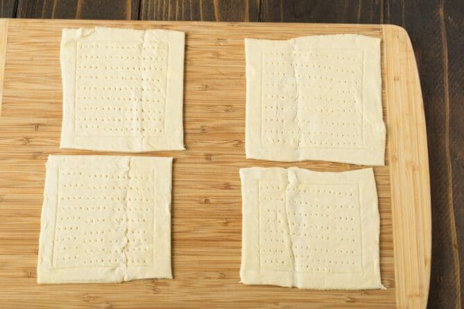 4 squares of puff pastry on a cutting board