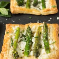 A closeup showing asparagus sprigs on top of a puff pastry tartlet