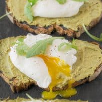A perfectly poached egg with the yolk running out onto avocado artichoke toast