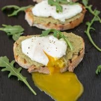 A very runny poached egg on top of avocado artichoke toast