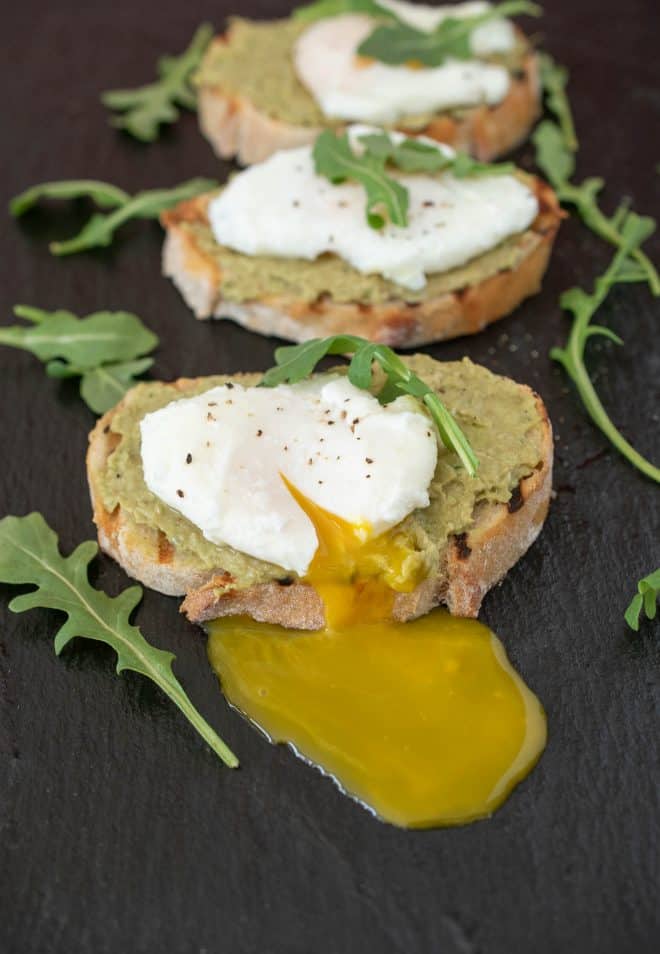 A very runny poached egg on top of avocado artichoke toast