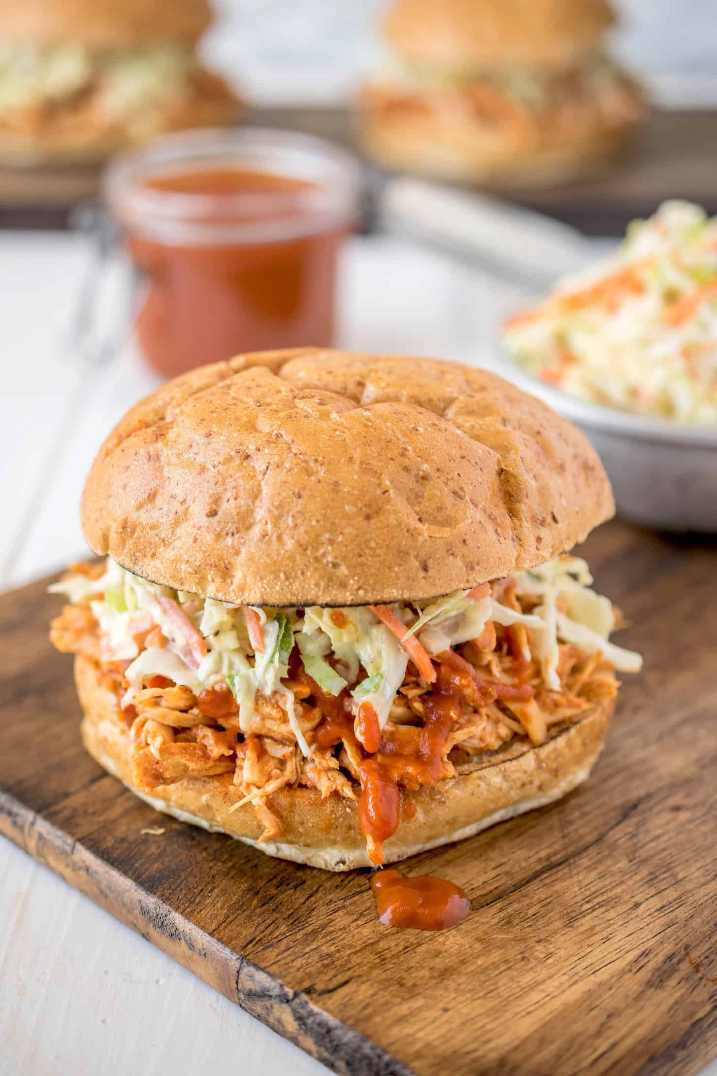 BBQ shredded chicken on a toasted bun topped coleslaw and dripping with barbecue sauce.