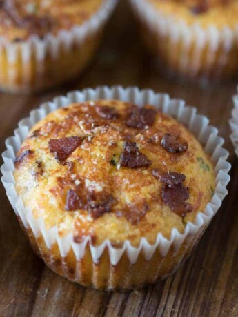 A bacon cheddar corn muffins with pieces of bacon on the top