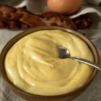 Creamy yellow mayonnaise in a bowl with a spoon
