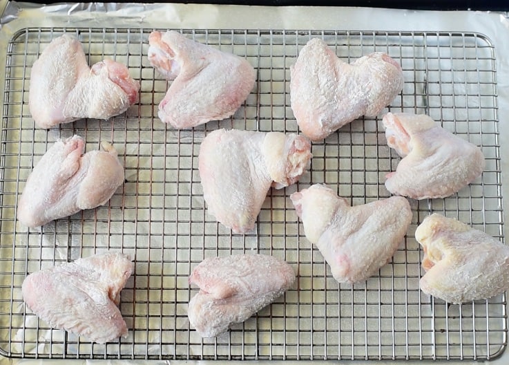 Flour coated chicken wings on a baking rack ready to be baked