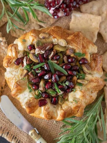 From overhead showing the pretty pomegranate seeds and rosemary on top of the baked brie