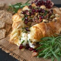 Creamy brie oozing out from the puff pastry with pomegranate seeds and pistachio nuts