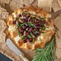 Puff pastry wrapped brie topped with nuts and pomegranate seeds served with crackers