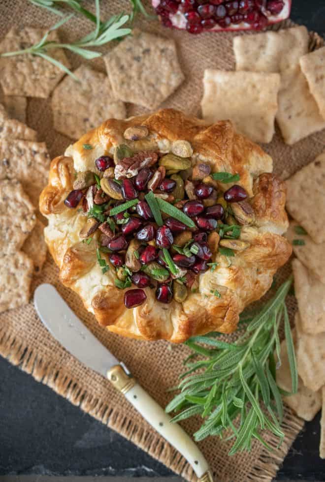 Baked Brie with Pistachios, Pomegranate and Rosemary wrapped in puff pastry surrounded with crackers