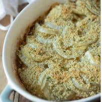 A closeup of sliced fennel and apple in a casserole dish topped with breadcrumbs