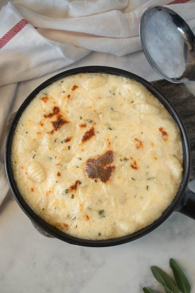 Baked gnocchi in cheese sauce viewed from overhead with a serving spoon