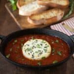 Baked herb goat cheese with marinara sauce in a black oval bowl