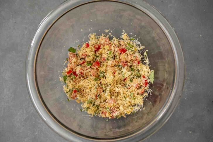 A bowl of breadcrumbs mixed with herbs and tomato