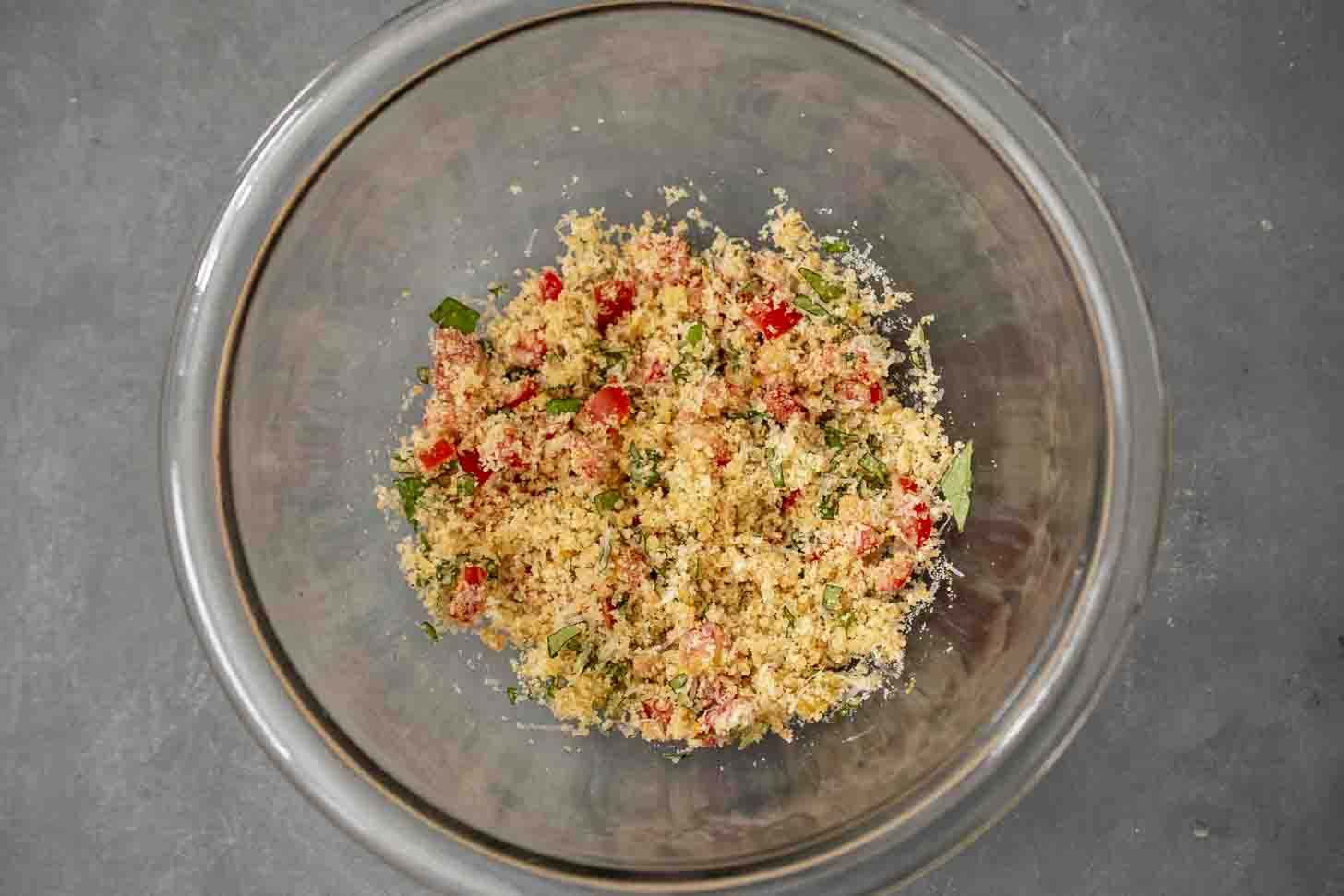 A bowl of breadcrumbs mixed with herbs and tomato