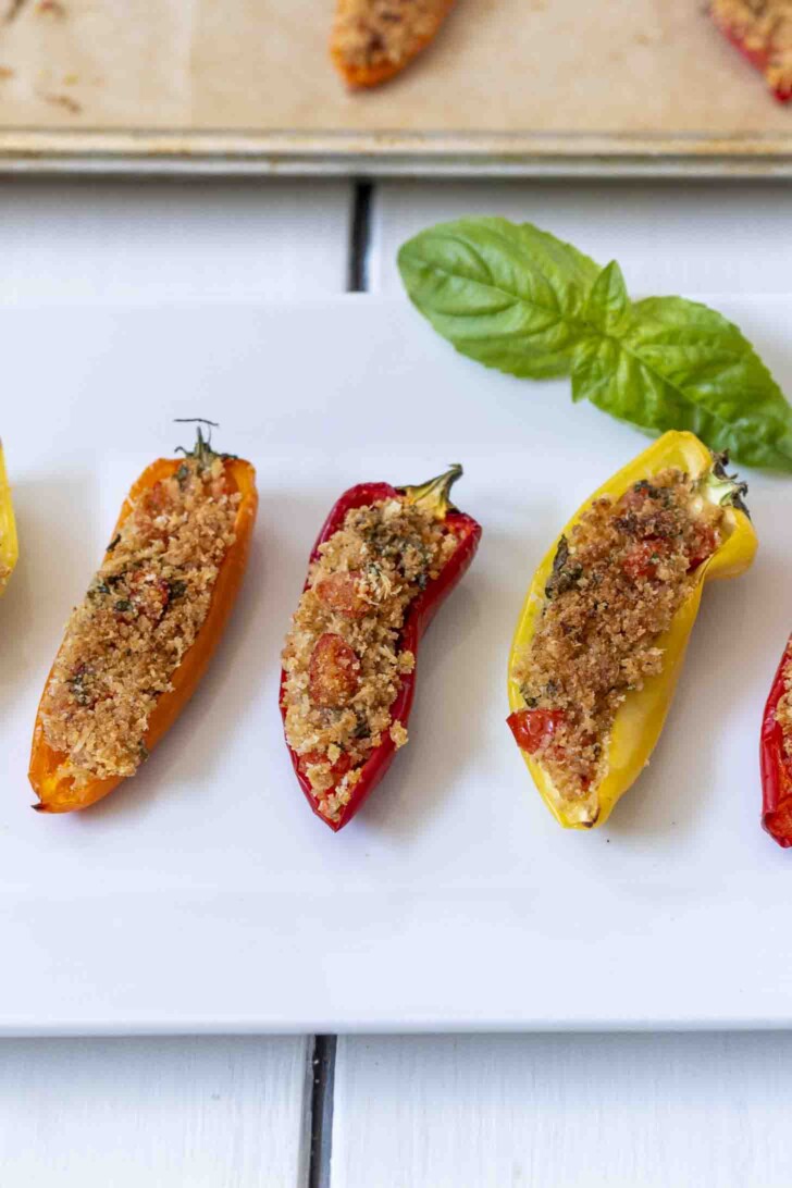 Small peppers stuffed with breadcrumbs on a white plate