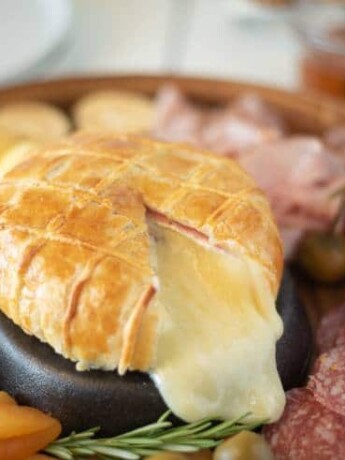 A cut open Baked Brie and Black Forest ham in puff pastry with lots of melted brie oozing out