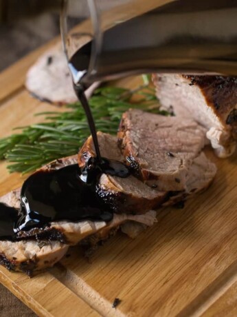 Juicy pork tenderloin slices being drizzled with thick balsamic glaze